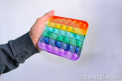 Male hand holding a rainbow Toy antistress Pop it, press rubber bubbles, concept entertainment, stress relief, development of fine Stock Photo