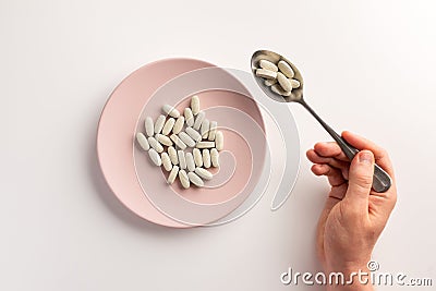 Male hand holding spoon with pills. Plate with pills. Stock Photo