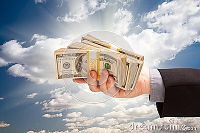 Male Hand Holding Stack of Cash Over Sky Stock Photo