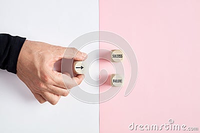 Male hand holding a wooden cube with arrow icon pointing at the options of success or failure. Decision making dilemma in business Stock Photo