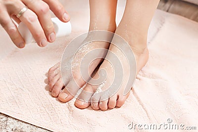 Male hand holds the container with the powder and pour the white powder on child`s feet. Medicine against sweating of the feet Stock Photo