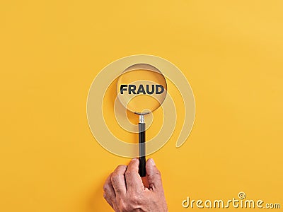 Male hand holds a magnifier focusing on the word fraud. To search, find, discover or reveal a fraud attempt Stock Photo