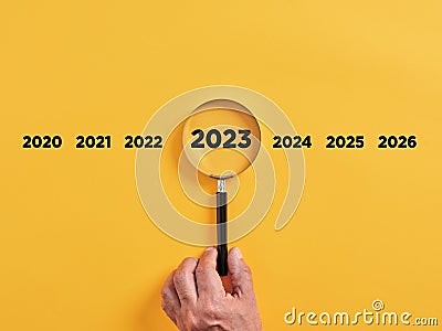 Male hand holds a magnifier focusing on the year 2023. Focus on new business goals, plan and strategy of the year 2023 Stock Photo