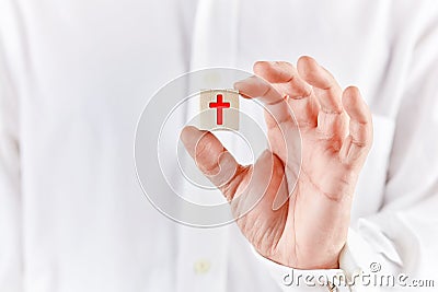 Male hand holds a wooden cube with the religious cross symbol. Christianity belief or religion Stock Photo