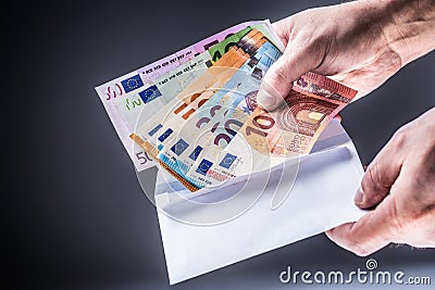 Male hand inserted into the envelope euro banknotes - bribe and corruption concept Stock Photo