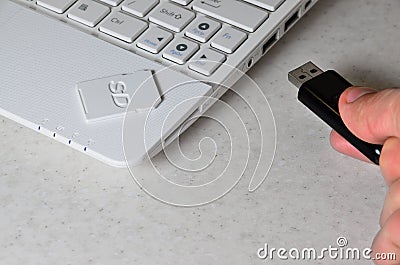 A male hand inserts a black compact USB card into the corresponding input in the side of the white netbook. Man uses modern techn Stock Photo