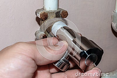 A male hand installs a distribution or shut-off water tap. Water connection to the washing machine or dishwasher. A plumber Stock Photo