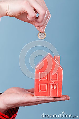 Male hand with little house and silver coin. Stock Photo