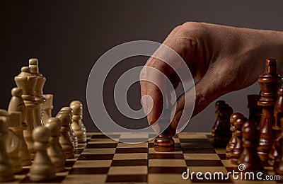 Male hand moving pawn on chess board, starting game and making first step. Making business decision concept Stock Photo