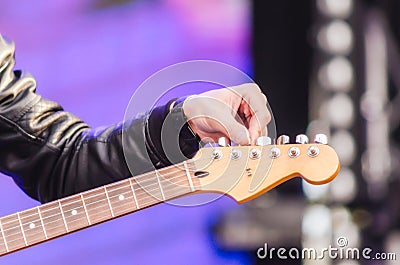 Male hand musician tunes guitar close up Stock Photo