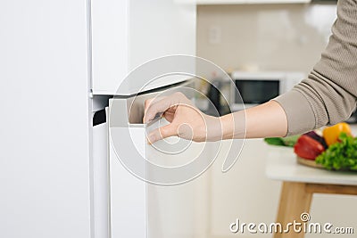 Male hand is opening white refrigerator door Stock Photo