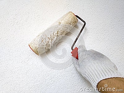 Male hand painting wall with roller. Renovating with white color paint Stock Photo