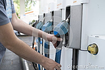 Male hand places gaspump nozzle back in the pump at the gasstation Stock Photo