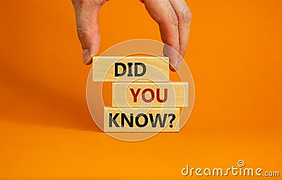 Male hand placing a block with word `did` on top of a blocks tower with words `did you know`. Beautiful orange background. Cop Stock Photo