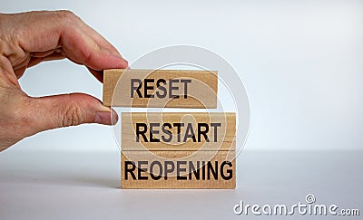 Male hand placing a blocks with word `reset` on top of a blocks tower with words `restart, reopening. Beautiful white backgroun Stock Photo