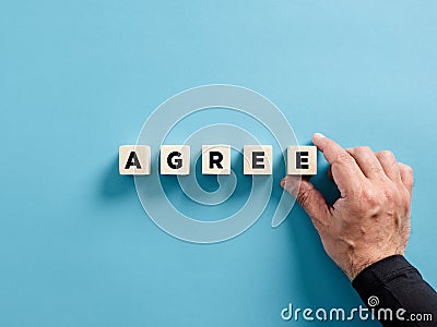 Male hand placing the wooden cubes with the word agree. To reach a business agreement Stock Photo