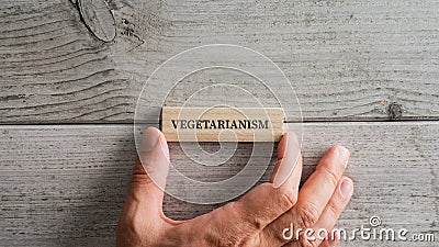 Placing wooden peg with a Vegetarianism sign on it over white wooden background Stock Photo