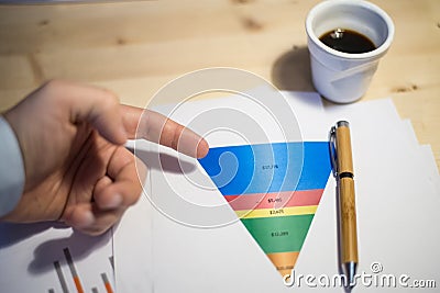 Male hand pointing at a sales funnel printed on a white sheet of paper during a business meeting Stock Photo