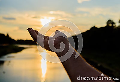 Male hand pointing at sun in blue sky at evening time admire landscape. Capture moment to admire sunset nature beauty Stock Photo