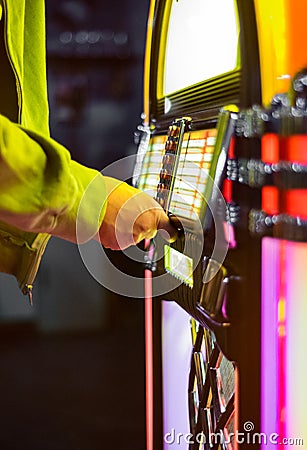 Male hand pushing buttons to play song on old Jukebox Stock Photo