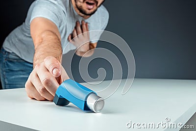 The male hand reaches for an asthma inhaler, an asthmatic attack. The concept of treatment of bronchial asthma, cough, allergies, Stock Photo