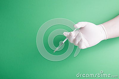 Male hand in rubber white medical disposable glove holds insulin syringe green background Stock Photo