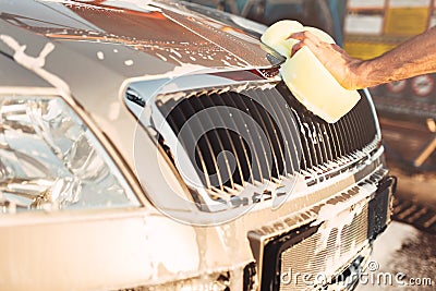 Male hand rubbing the car with foam, carwash Stock Photo