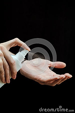 Male hand with a sanitizer spray disinfect his hand in the house on a black background. Covid-19 Coronavirus Quarantine Stock Photo