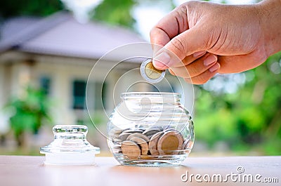 Male hand saving money coins with hom Stock Photo