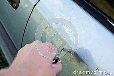 male hand scratches car wing with key Stock Photo