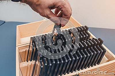 Male hand selects a lens. Set of optical lenses in a wooden box. Optics Stock Photo