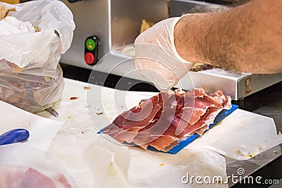 Male hand slicing raw ham with a machine to be packed, Croatia Stock Photo