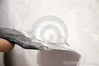 Male hand with a spatula putty wall. . Align the wall. White wall. Putty on the wall Stock Photo