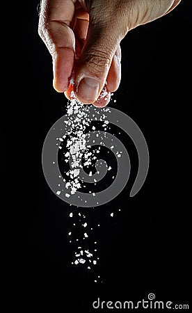 Male hand sprinkling edible salt at black background Stock Photo