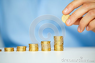 Male hand stacking gold coins into increasing columns Stock Photo