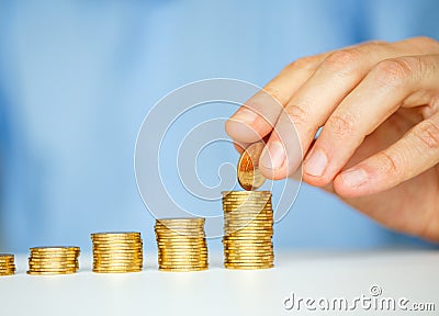 Male hand stacking gold coins into increasing columns Stock Photo