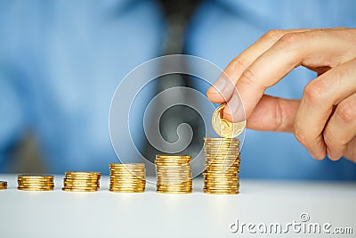 Male hand stacking gold coins into increasing columns Stock Photo