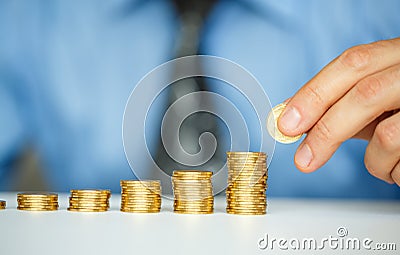 Male hand stacking gold coins into increasing columns Stock Photo