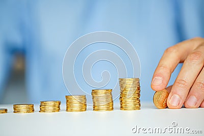 Male hand stacking gold coins into increasing columns Stock Photo