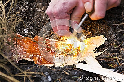 Male hand starts fire with magnesium fire steel, fire striker Stock Photo