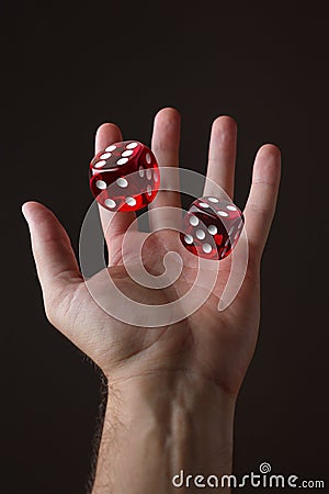 Male hand throwing playing dices on dark background. Luck and fortune concept Stock Photo