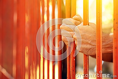 Male hands behind prison yard bars Stock Photo