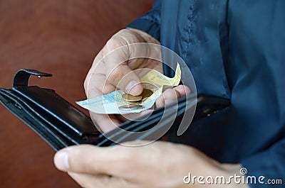 A male hands with coins with small Ukrainian bills and black old purse Stock Photo