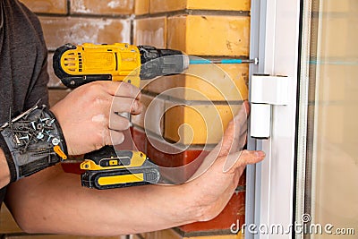Male hands of construction worker tighten and fix screws and self-tapping screw with electric cordless screwdriver for home Stock Photo