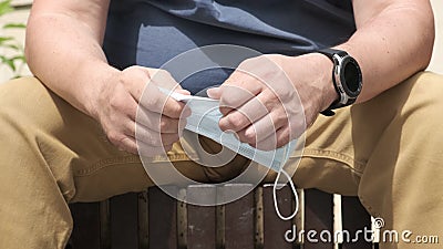 Male hands crumpling a medical protective face mask, close-up Stock Photo