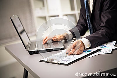 Male hands doing paperwork with pen and laptop. Stock Photo