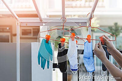 Male hands are hanging cloth or fabric mask after washing clean mask dry disinfect for wearing reuse. Concept of good hygine and Stock Photo