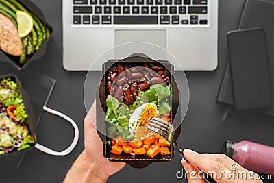 Male hands holding food delivery box eating lunch at work in office, flat lay. Stock Photo