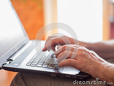 Male hands with a keyboard of laptop, closeup, selective focus. Person working at home. Stock Photo