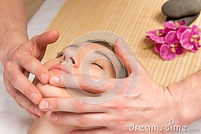 Male hands of the masseur, cosmetologist, doing massage the girl Stock Photo